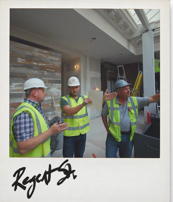 Photo, Anthropologie Regent Street, London, during the fit-out: three people in hard hats, one pointing up at a skylight