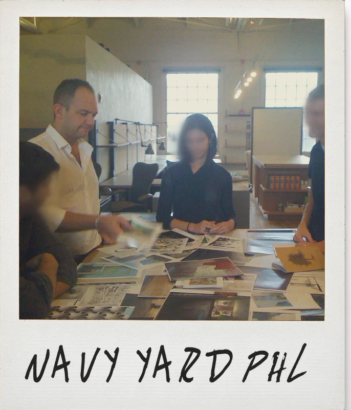 Photo, URBN’s design studio at the Navy Yard, Philadelphia: James with his team around a table covered in prints, their faces softly blurred
